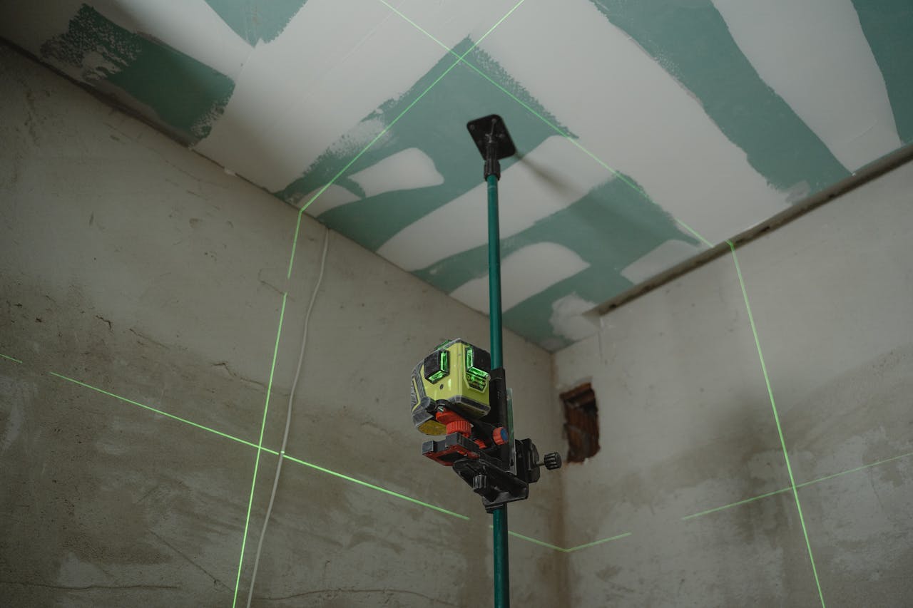 about-img-01 A laser level tool in action at an indoor construction site with marked walls.